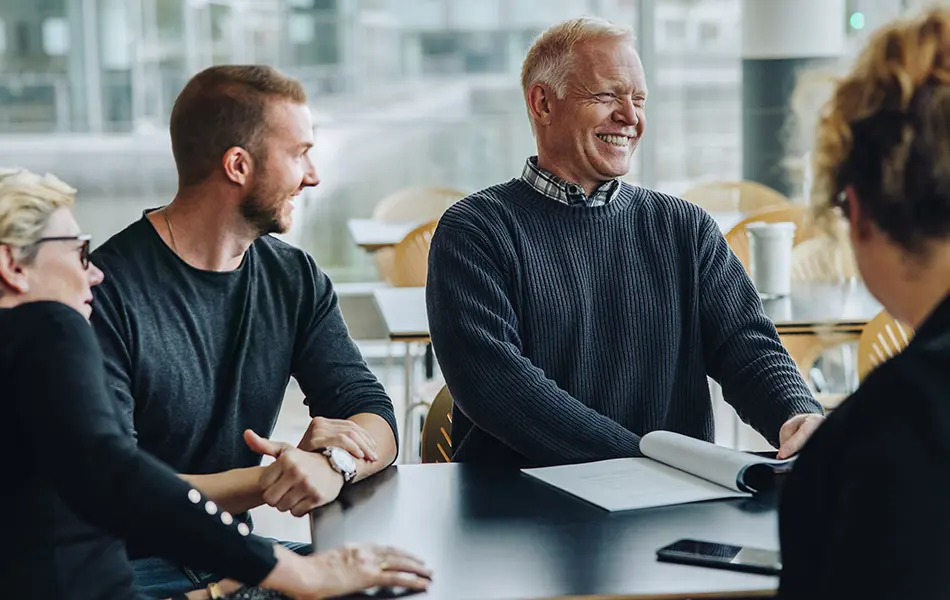 Kollegor skrattar och samarbetar på kontoret.