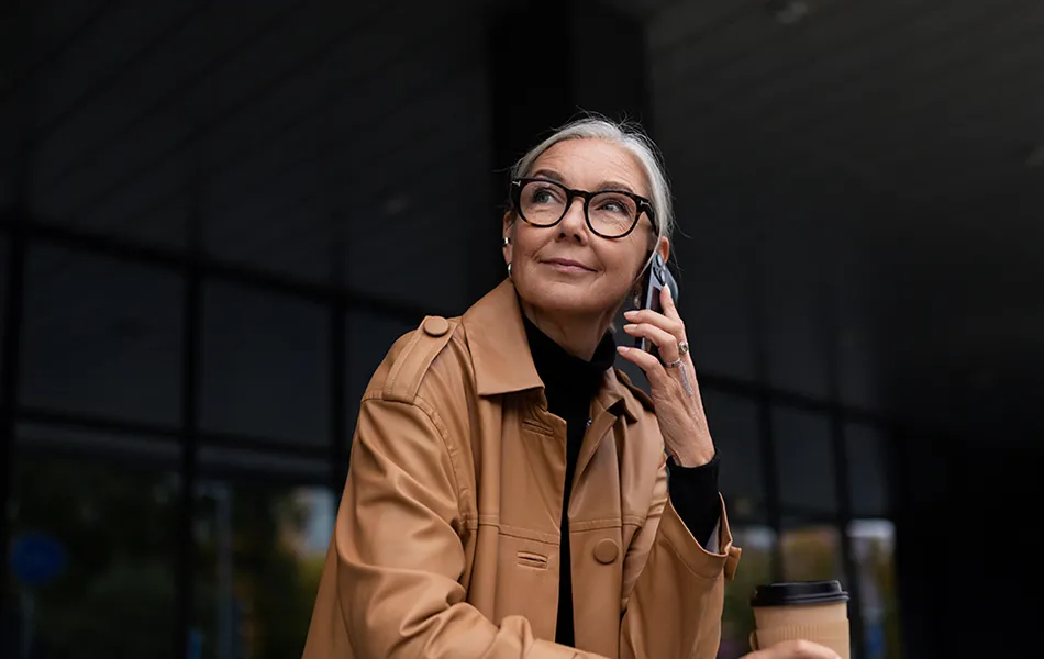 Kvinna talar i mobiltelefon utanför kontorsbyggnad.